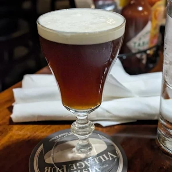 Irish coffee with a thick layer of cream, on a Vista Village Pub coaster.